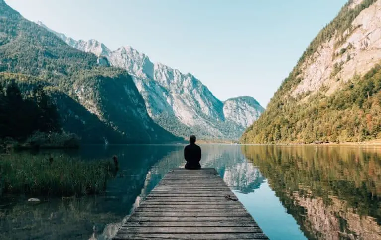 self-reflection-a-person-sitting-on-wooden-planks-across-the-lak