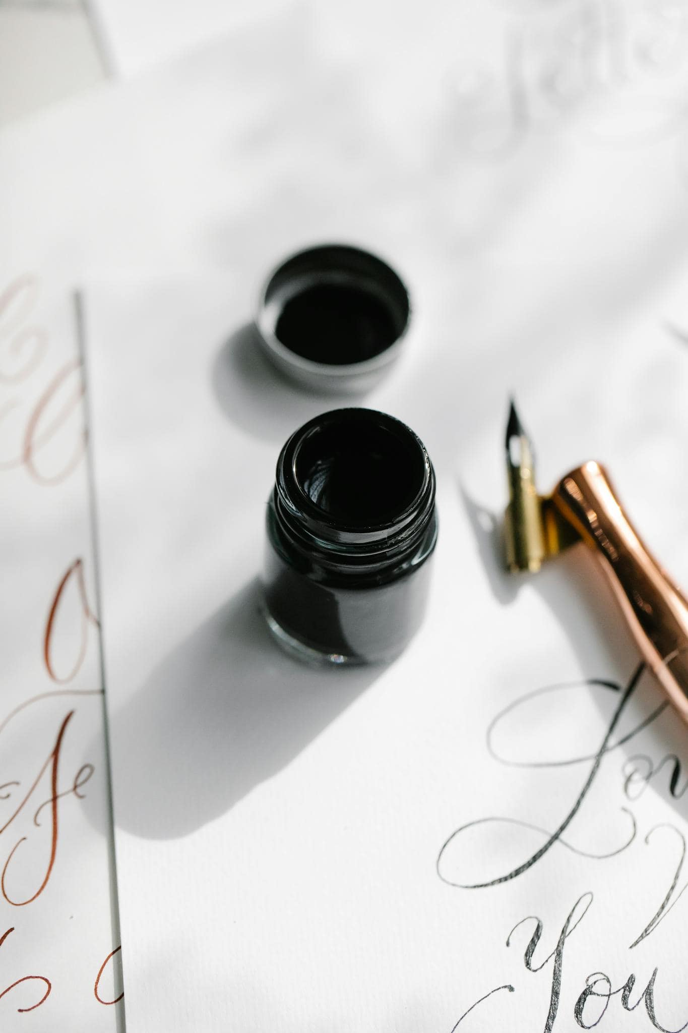 Close-up of a fountain pen and ink bottle on calligraphy paper, ideal for artistic themes.